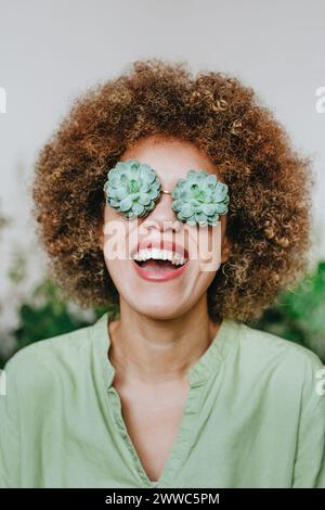Donna allegra che indossa occhiali da vista con fiori di echeveria Foto Stock