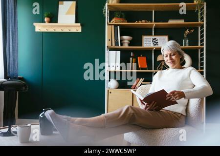Donna matura leggere libro a casa Foto Stock