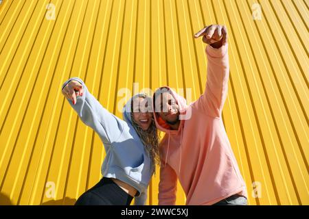 Coppia felice che gestiva un cartello di pace di fronte al muro giallo Foto Stock