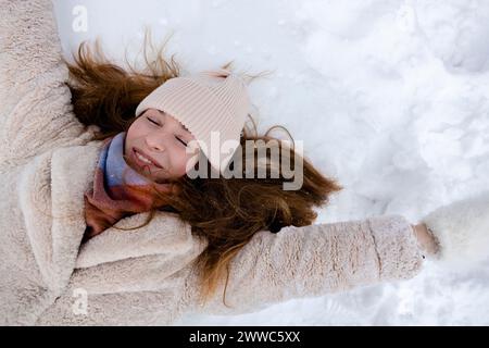 Sorridente giovane donna stesa sulla neve Foto Stock