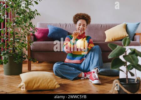 Giovane donna felice che mette la moneta nel salvadanaio a casa Foto Stock