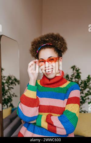 Giovane donna felice che indossa occhiali da sole di colore arancione Foto Stock