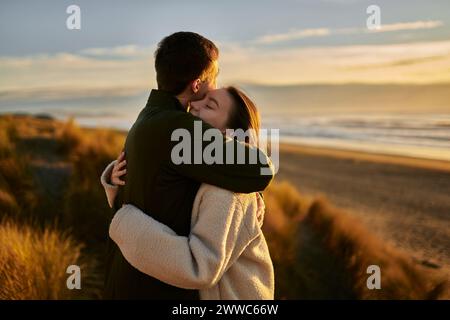 Giovane che abbraccia la ragazza in spiaggia Foto Stock