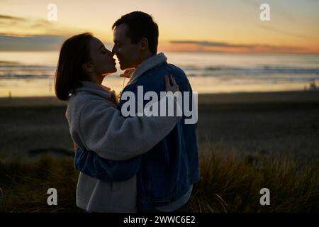 Fidanzata e fidanzato affettuosi che abbracciano la spiaggia al tramonto Foto Stock