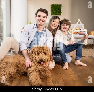 Famiglia felice con casa modello e cane a casa Foto Stock