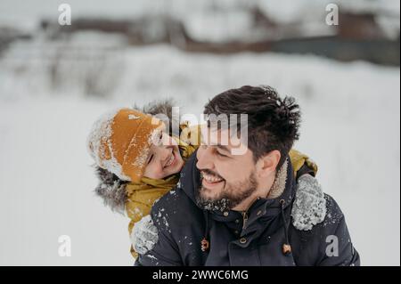 Uomo felice che si diverte con il figlio sulla neve in inverno Foto Stock