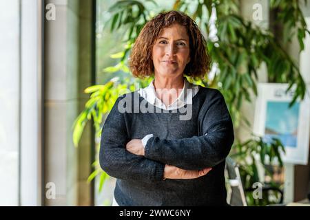 Donna d'affari matura sorridente in piedi con le braccia incrociate in ufficio Foto Stock
