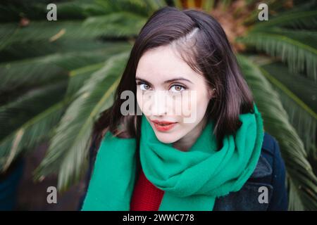 Bella donna sorridente vicino alla pianta Foto Stock