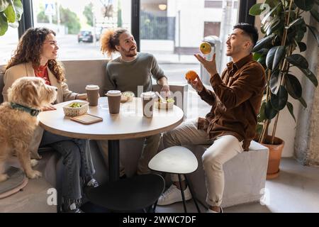 Uomo d'affari che giocherà frutta seduto con i colleghi al bar dell'ufficio Foto Stock