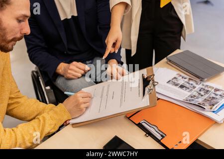 Uomo d'affari che firma un accordo in ufficio Foto Stock