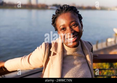 Donna felice in piedi vicino al fiume al tramonto Foto Stock