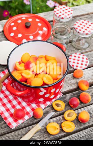 Preparazione della marmellata di albicocche su un tavolo da giardino in legno Foto Stock