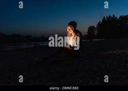 Donna sorridente che utilizza lo smartphone di notte Foto Stock