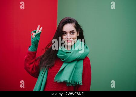 Donna sorridente in piedi e mostra un cartello di pace davanti al muro Foto Stock