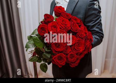 Adolescente che tiene a casa un bouquet di rose rosse Foto Stock