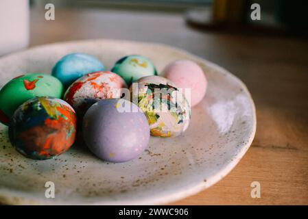 Uova di Pasqua colorate disposte in piatto a casa Foto Stock