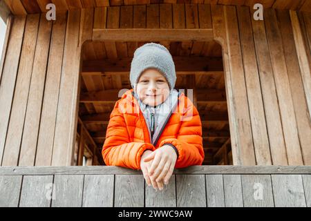 Ragazzo sorridente appoggiato su ringhiera di legno in cabina Foto Stock