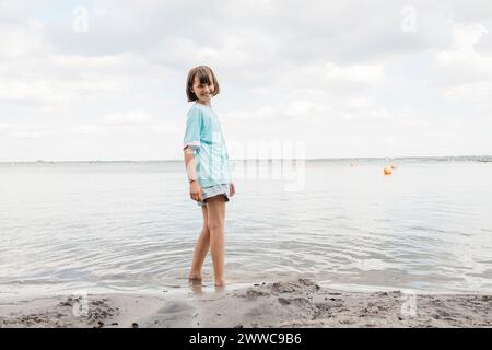 Ragazza felice in piedi vicino a riva sul lago Foto Stock