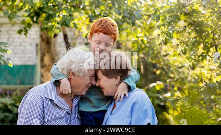 Felice coppia anziana con faccia a faccia vicino al nipote in giardino Foto Stock