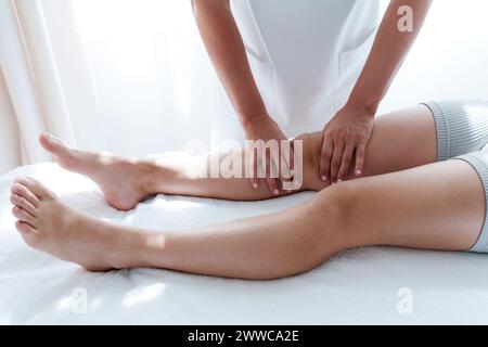 Osteopata che offre massaggio al paziente al ginocchio nella sala di trattamento Foto Stock