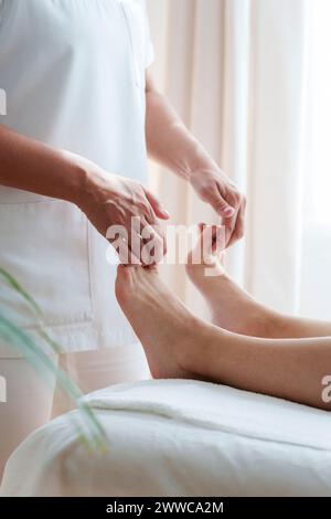 Osteopati che trattano i piedi del paziente nella sala di trattamento Foto Stock