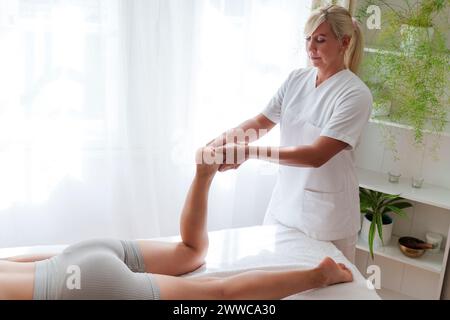 Fisioterapista che fa massaggio ai piedi al paziente nella sala di trattamento Foto Stock