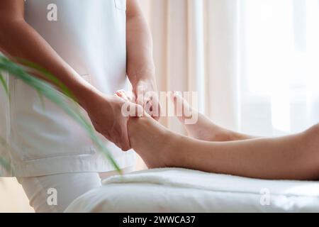 Osteopata che tratta i punti di pressione sul piede del paziente nella sala di trattamento Foto Stock