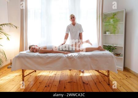 Osteopata che offre massaggio al paziente sdraiato sul tavolo nella sala di trattamento Foto Stock