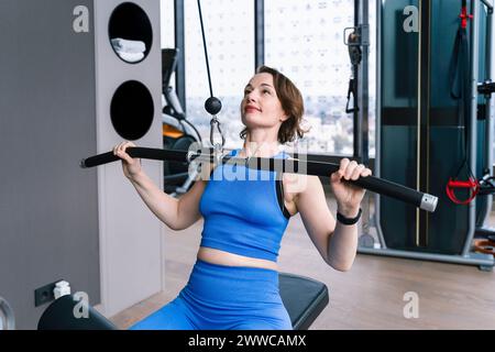 Donna matura che fa esercizio su una macchina laterale per il sollevamento in palestra Foto Stock