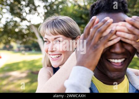 Donna felice che copre gli occhi di amico al parco Foto Stock