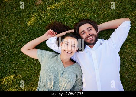 Felice coppia giovane sdraiato sull'erba Foto Stock