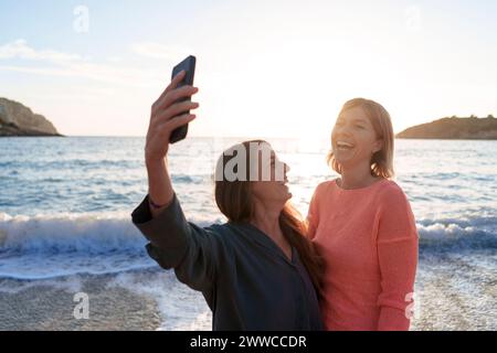 Amici allegri che scattano selfie insieme sulla spiaggia Foto Stock