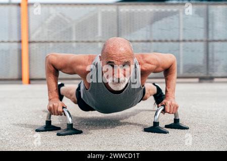 Un uomo anziano determinato che fa esercizio sulle maniglie Foto Stock