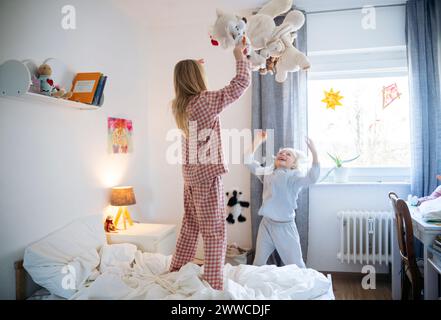 Fratelli giocosi che gettano orsacchiotto nella camera da letto di casa Foto Stock