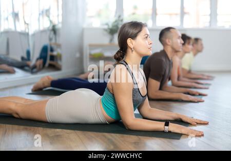 Gli amanti dello stile di vita attivo sul tappetino yoga si esibiscono facendo posa di cobra serpente, bhujangasana in palestra Foto Stock