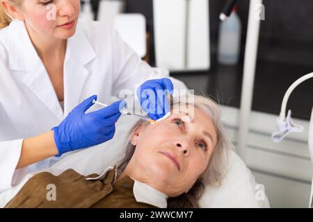 Donna anziana che riceve la botulinoterapia per il suo viso Foto Stock