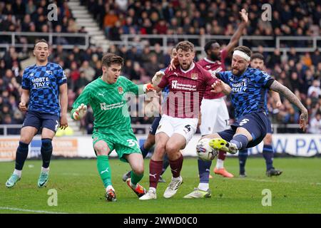 Sonny Bradley (a destra) del Derby County ha il suo tiro salvato dal portiere del Northampton Town Louie Moulden durante la partita Sky Bet League One al Sixfields Stadium di Northampton. Data foto: Sabato 23 marzo 2024. Foto Stock