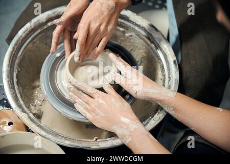 Donne irriconoscibili che realizzano caraffe d'argilla che scolpiscono in laboratorio sulla ruota di vasaio Foto Stock
