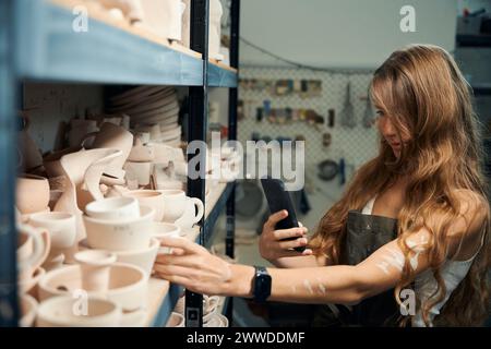 Ceramiche e donne con telefono cellulare che fanno foto di lavori professionali in argilla Foto Stock