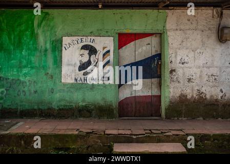 Un muro eroso con un murale dipinto di una bandiera e di un ritratto, Nicaragua Foto Stock