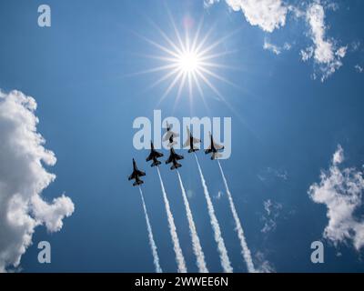 Un gruppo di jet da combattimento vola in formazione nel cielo. Il sole splende brillantemente, creando una scena bella e dinamica. Concetto di potenza, precisione, Foto Stock