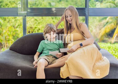 La madre in attesa condivide con tenerezza la gioia del suo bambino non ancora nato con suo figlio, mostrandogli le commoventi foto a ultrasuoni del suo piccolo che arriverà presto Foto Stock