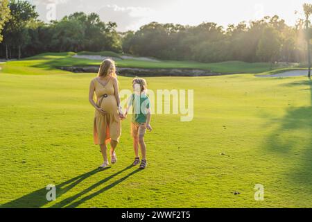 Mentre una mamma incinta e suo figlio si divertono insieme, assaporando la bellezza della natura e creando momenti preziosi Foto Stock