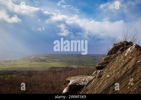 Vista panoramica da un affioramento roccioso che si affaccia su una lussureggiante valle sotto un cielo nuvoloso drammatico a Brimham Rocks, nel North Yorkshire Foto Stock