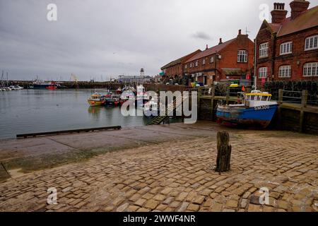 Barche da pesca ormeggiate in un porto sotto cieli grigi invernali ed edifici sul porto di Scarborough, North Yorkshire. Foto Stock