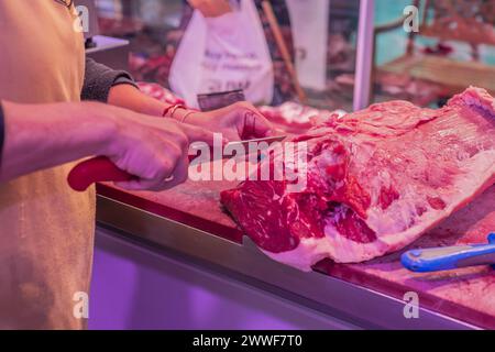 closeup shot, un'abile macelleria femminile affetta meticolosamente una tenera bistecca di manzo con precisione e competenza utilizzando il suo coltello affilato nel butch Foto Stock