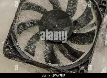 Primo piano della ventola del case del computer congelata in blocco di ghiaccio. Concetto: Tenere il computer fresco Foto Stock