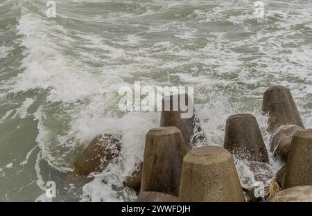 Onde oceaniche instabili si schiantano contro blocchi di cemento che controllano l'erosione in una giornata nuvolosa, a Ulsan, Corea del Sud Foto Stock