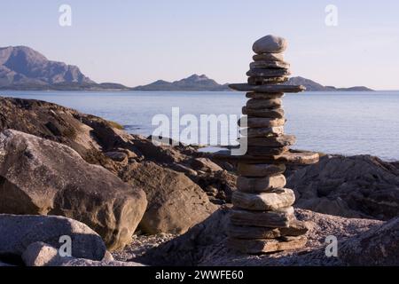 Sassi bilanciati su un tranquillo paesaggio costiero con un panorama montano sullo sfondo di Steinmann Lofoten Norvegia Foto Stock