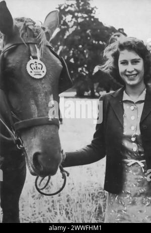 Una fotografia cattura Elisabetta II con uno dei cavalli di suo padre, nella tenuta reale di Sandringham nel 1943. Questa immagine mostra il legame precoce della giovane principessa con i cavalli, una passione che avrebbe continuato per tutta la sua vita Foto Stock